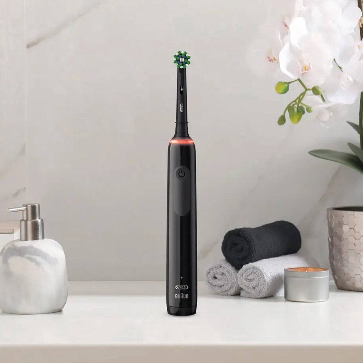 Oral-B PRO 3 3000 CrossAction Black Edition rechtop op badkamerblad tussen handdoekjes en bloemen