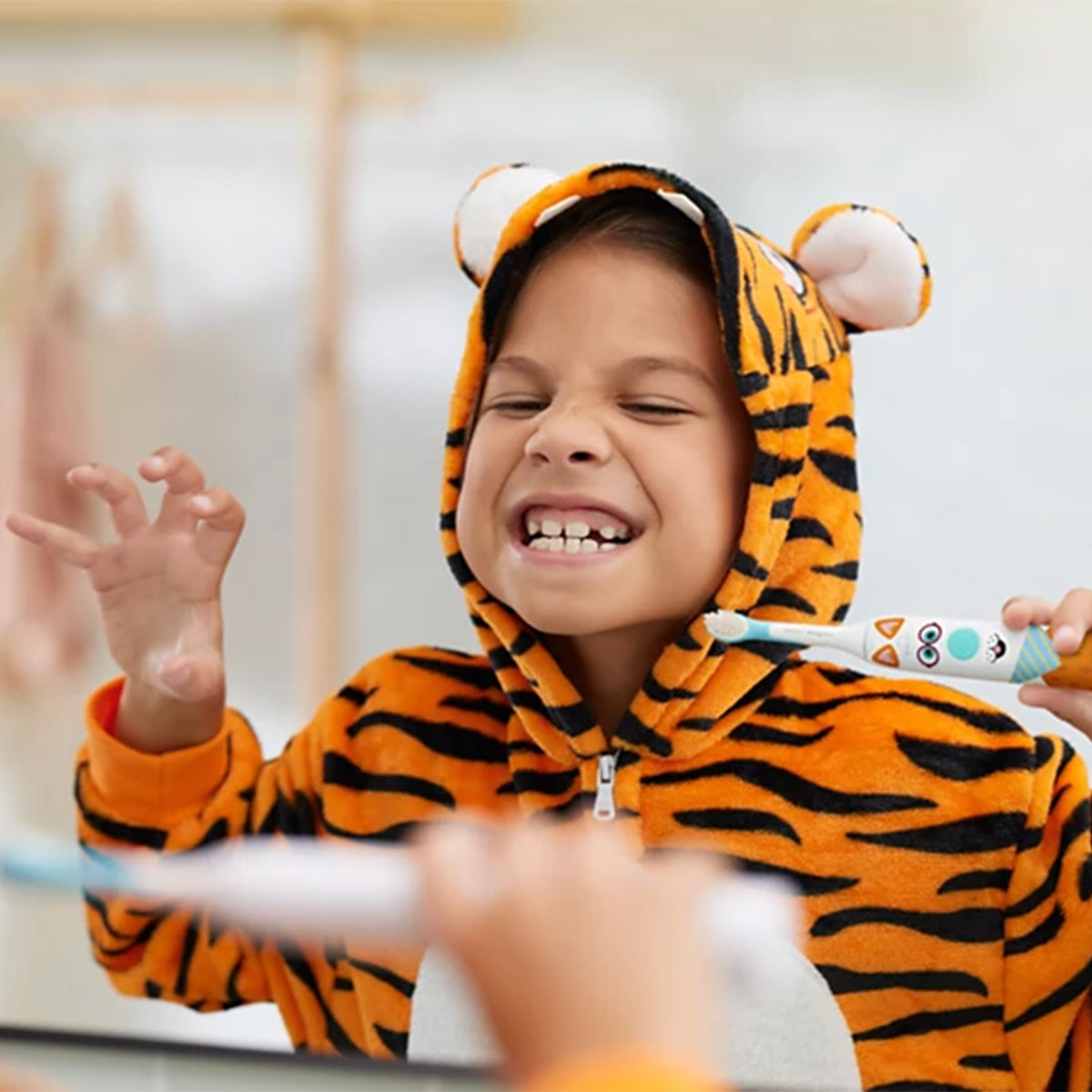 Sonicare For Kids elektrische tandenborstel, lachend kind in tijgerpak poetst voor spiegel