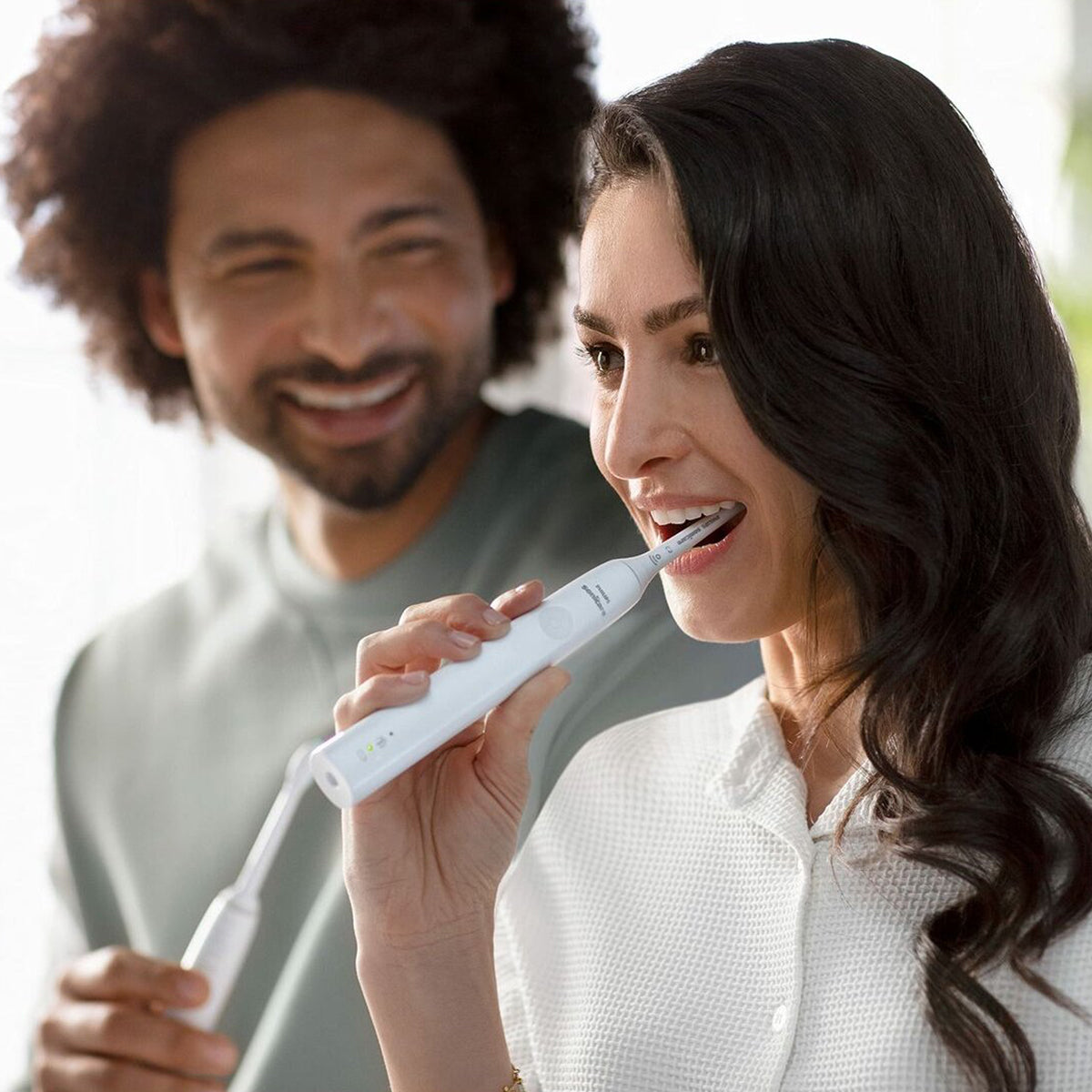 Sonicare 2100 witte elektrische tandenborstel tijdens gebruik door lachende vrouw