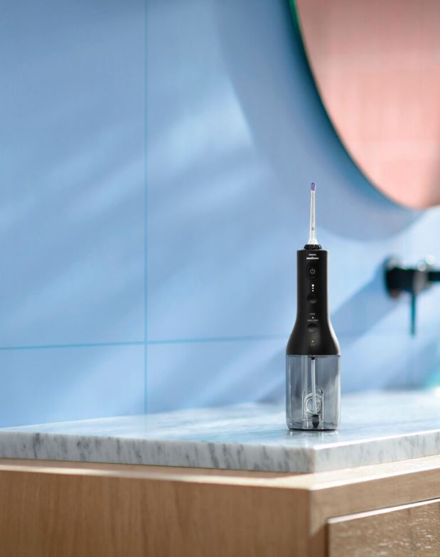 Sonicare Cordless Powerflosser 3000 op marmeren badkamerblad met blauwe tegelwand