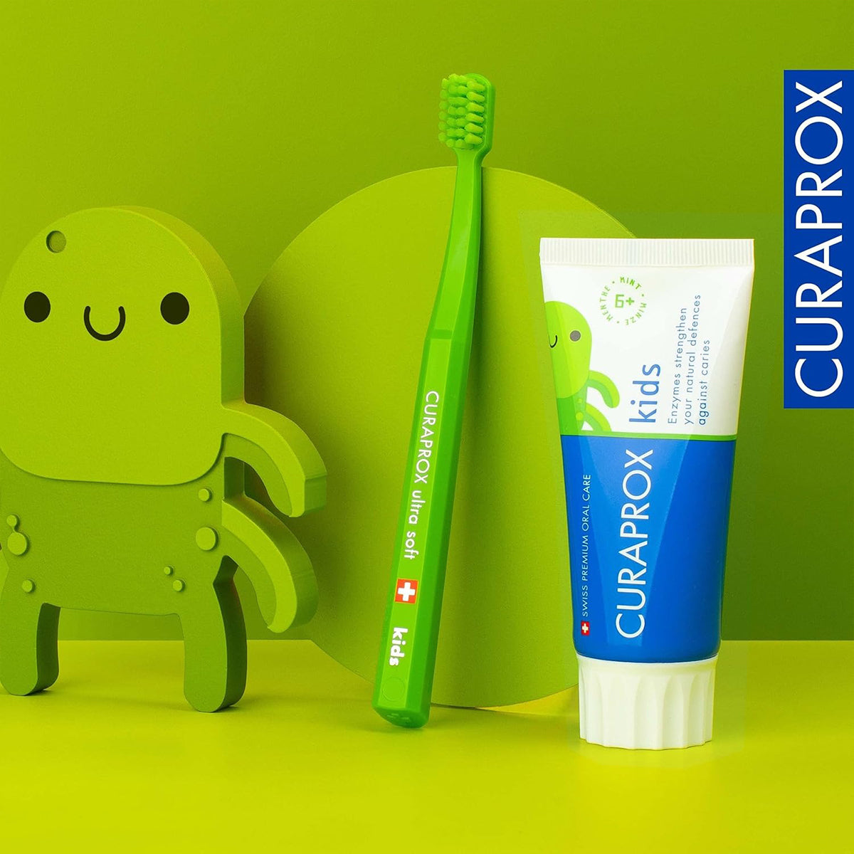 Curaprox Kinder tandpasta munt 6+ met groene kindertandenborstel op groene achtergrond