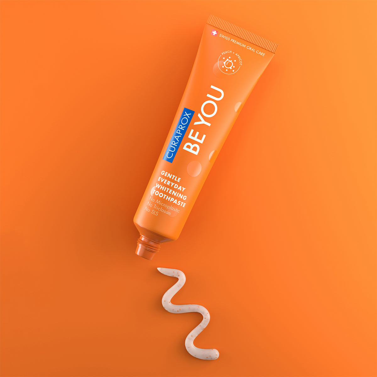 Curaprox BE YOU tandpasta perzik/abrikoos tube met uitgeknepen tandpasta op oranje achtergrond