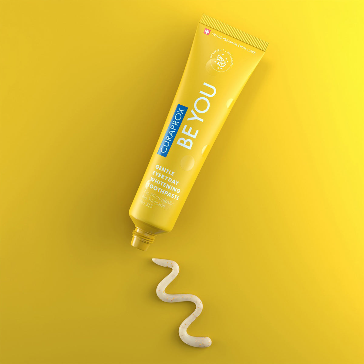 Curaprox BE YOU tandpasta grapefruit/bergamot met uitgeknepen sliert op gele achtergrond