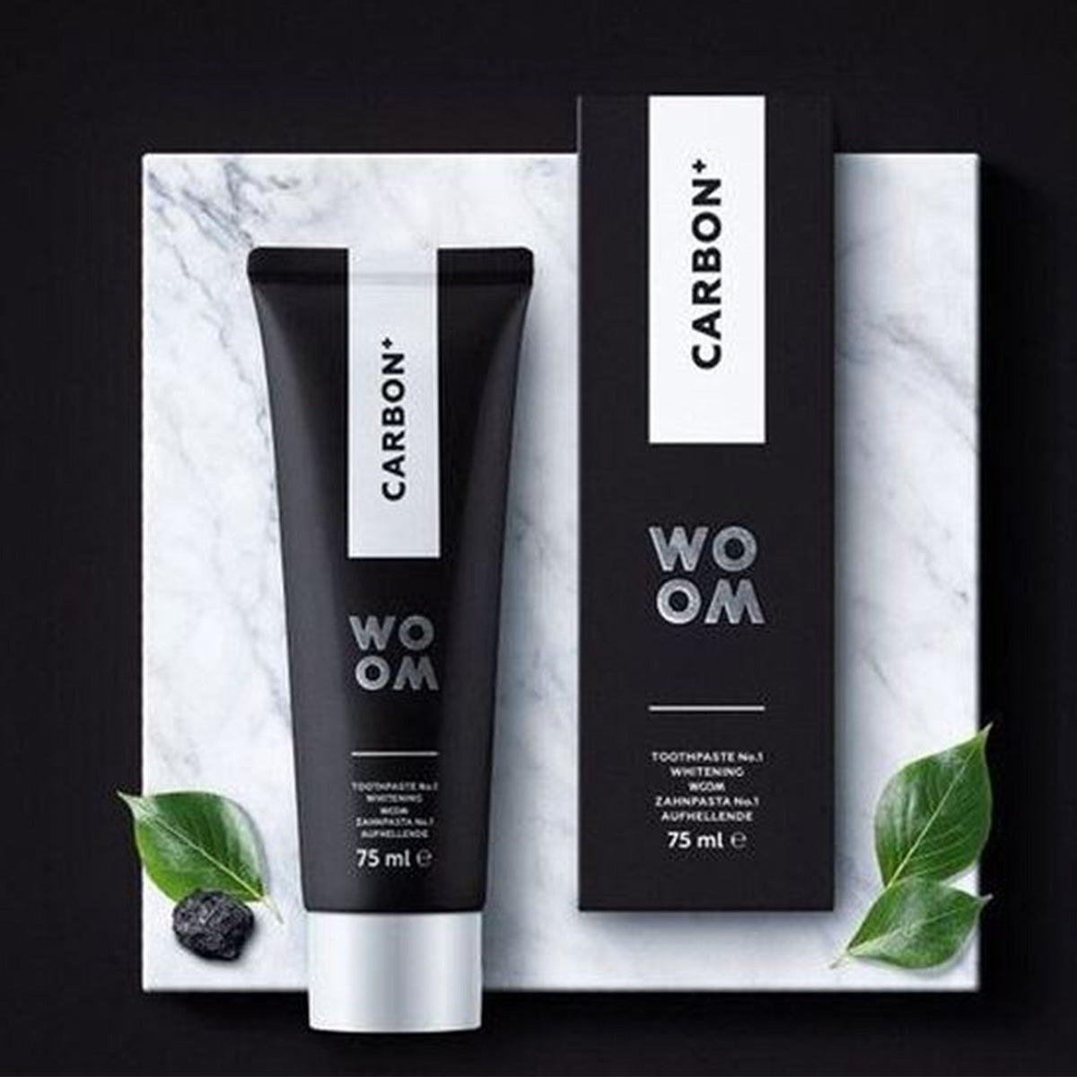 Woom tandpasta Carbon+ tube en verpakking van 75 ml op marmer
