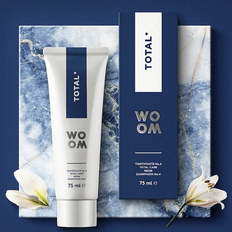 Woom tandpasta Total+ tube en verpakking op marmeren ondergrond met bloemen