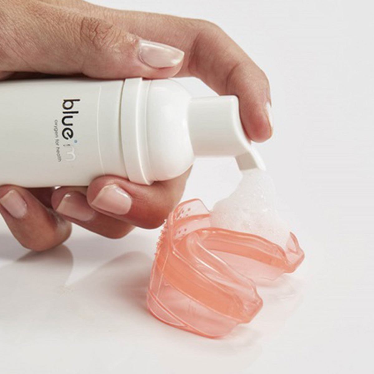 Bluem Oral Foam schuim aangebracht op oranje mondbitje uit witte flacon