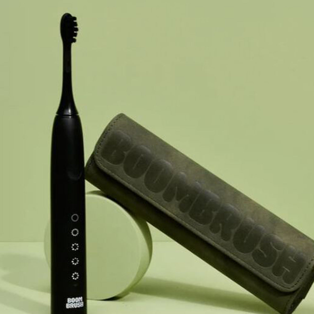 Boombrush travelcase in groen suède naast zwarte elektrische tandenborstel