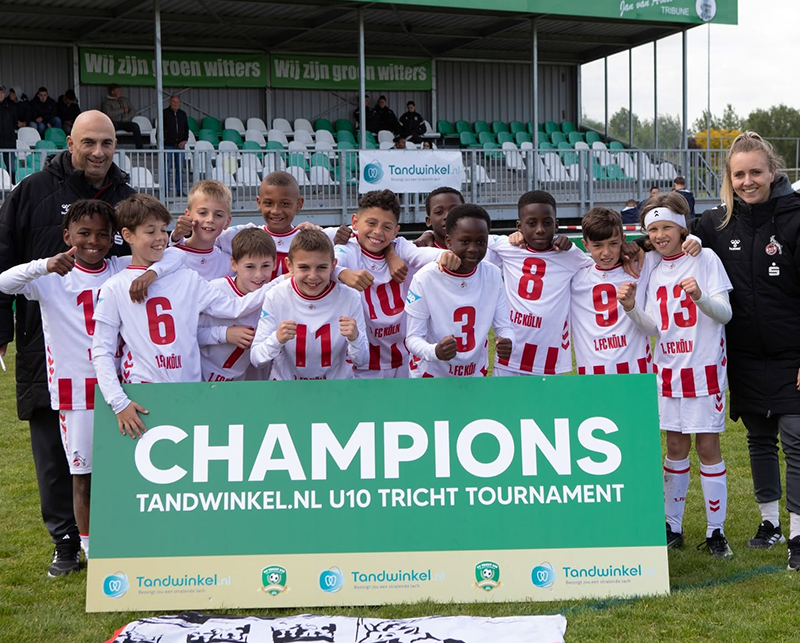 Voetbalteam met bord Champions Tandwinkel.nl U10 Tricht Tournament op stadion